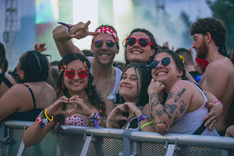 Group of friends wearing sunglasses at an outdoor music festival in the sun
