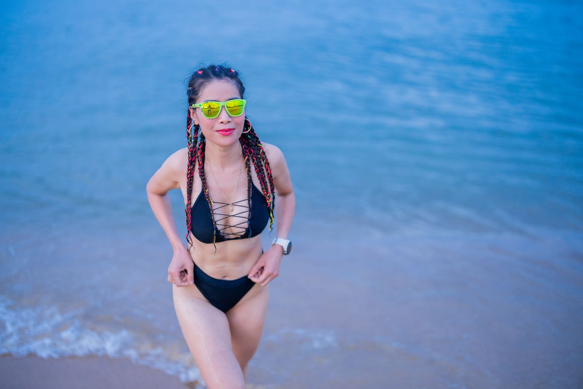 Person wearing wraparound shield sunglasses on a sunny Southern California beach boardwalk